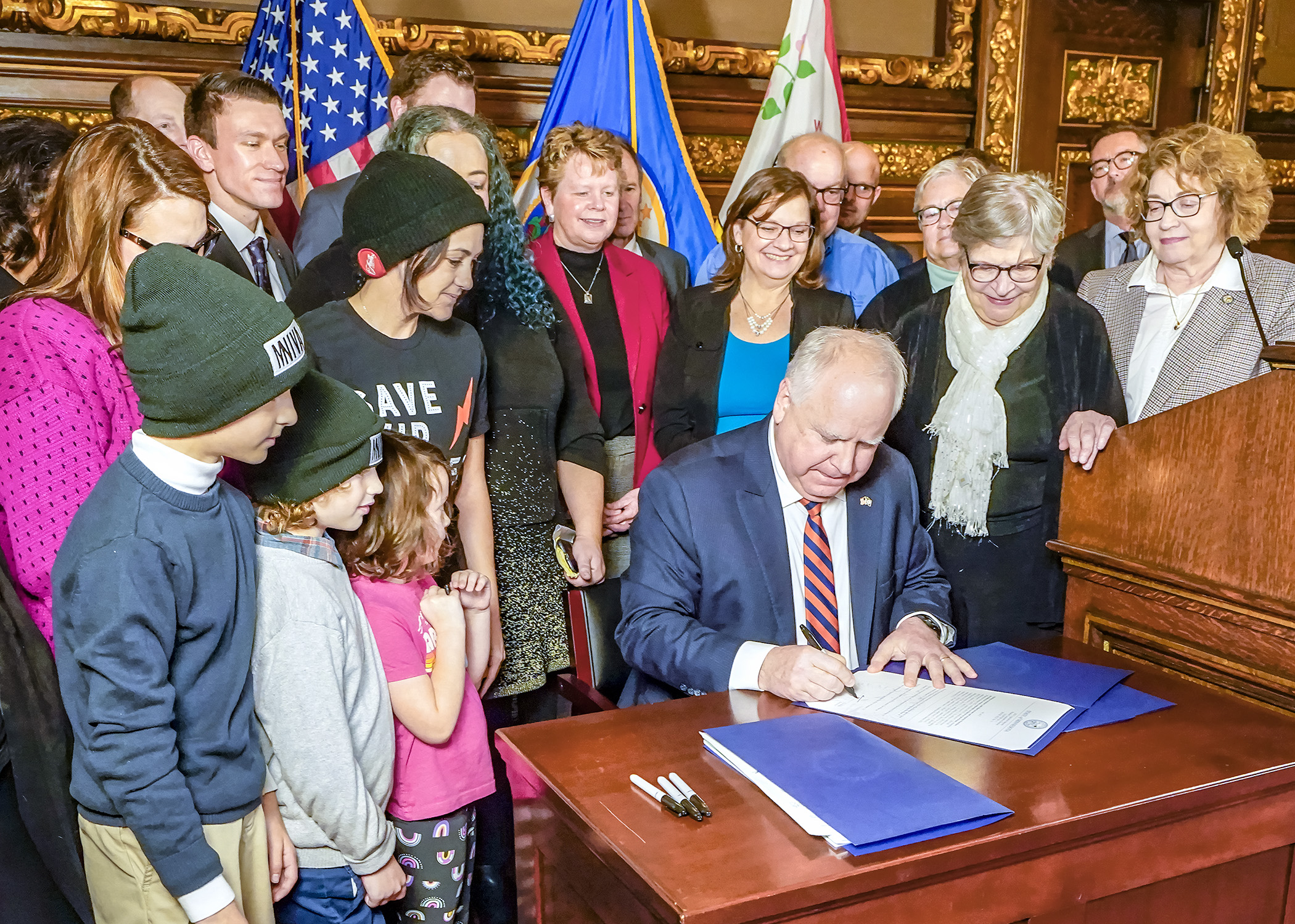 Surrounded by state lawmakers, officials and other attendees, Gov. Tim Walz signs the tax conformity bill into law Jan. 12 — the first bill to become law in the 2023 session. (Photo by Andrew VonBank)
